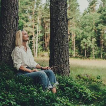 Kvinna vilar mot ett träd i skogen