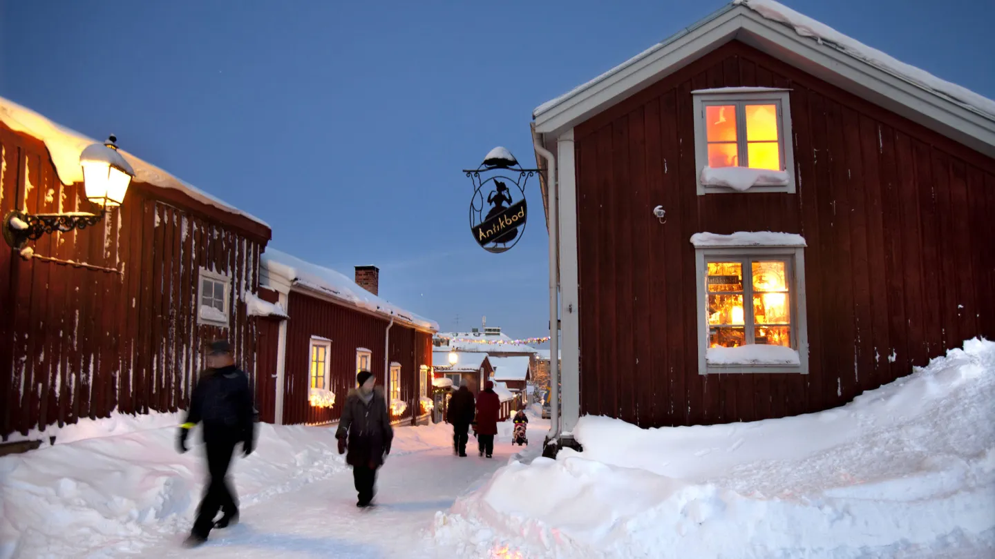 Gågata med massor av snö mellan röda hus en klar vinterkväll 