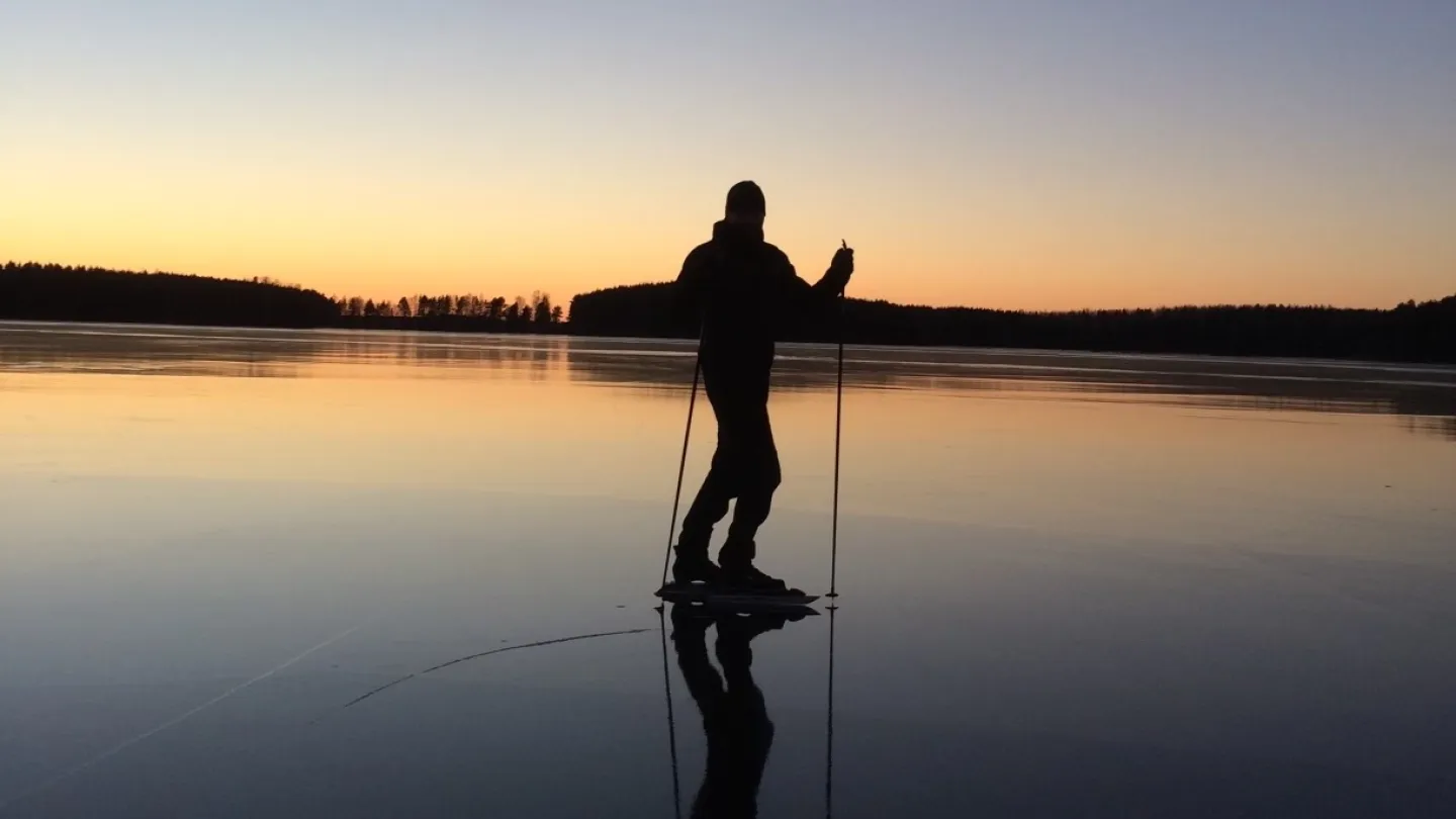 Skridskoåkare på blankis i skymnin