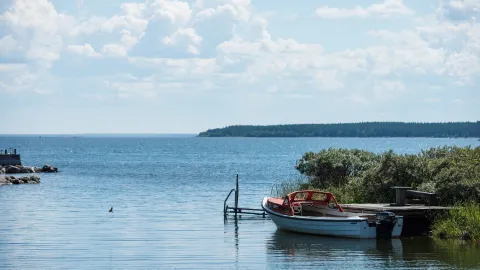 Liten öppen båt ligger förtöjd vid en liten brygga