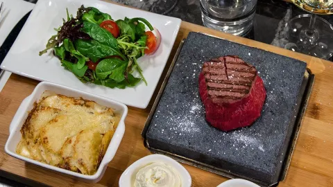 Sallad, ugnspotatis och en raw steak upplagd på planka