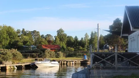 En kanal med en förtöjd motorbåt till vänster och en veranda till höger om kanalen