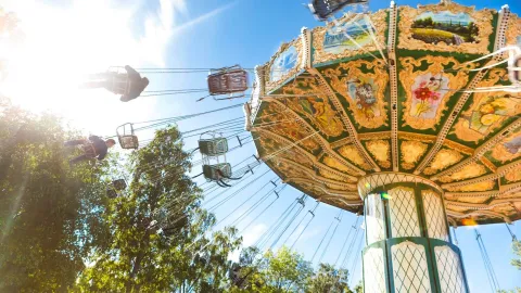 Slänggunga med passagerare far i luften en fin sommardag